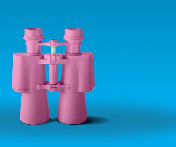 Pink binoculars on blue background